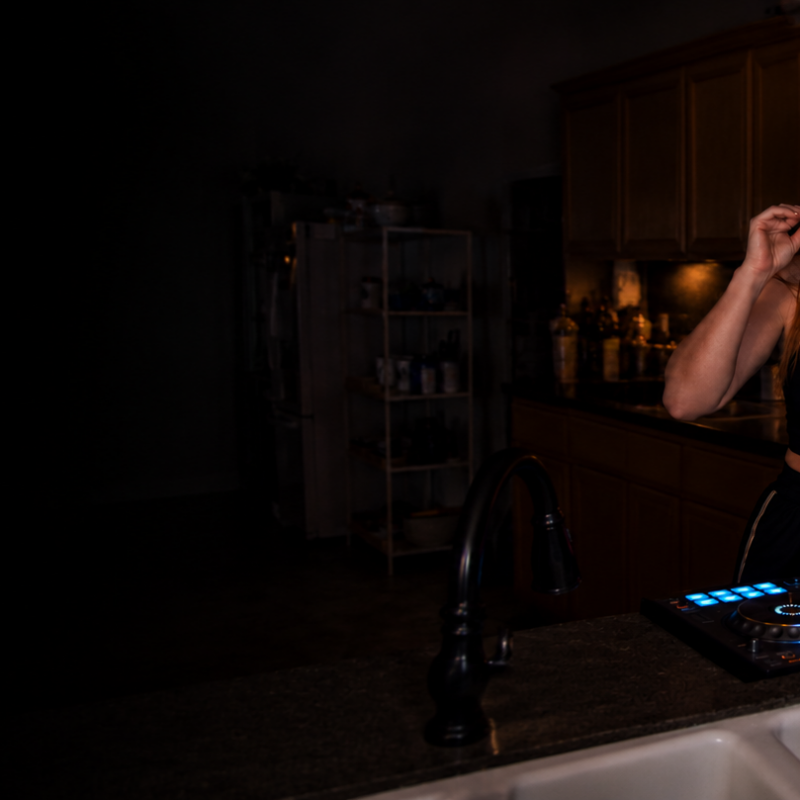 Female DJ eating potato chips in a kitchen at 2 AM while mixing music on a DJ controller, illustrating late-night snacking habits, irregular schedules, and nutrition challenges for DJs, musicians, and nightlife professionals.